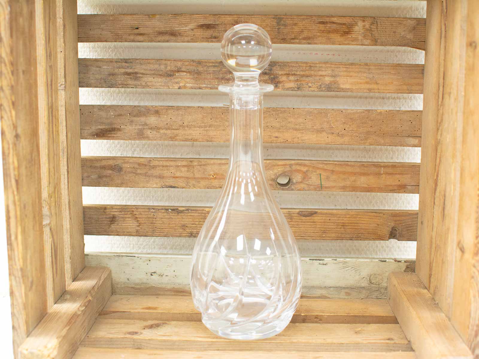 Elegant glass decanter in rustic wooden crate, perfect for enhancing home gatherings and decor.