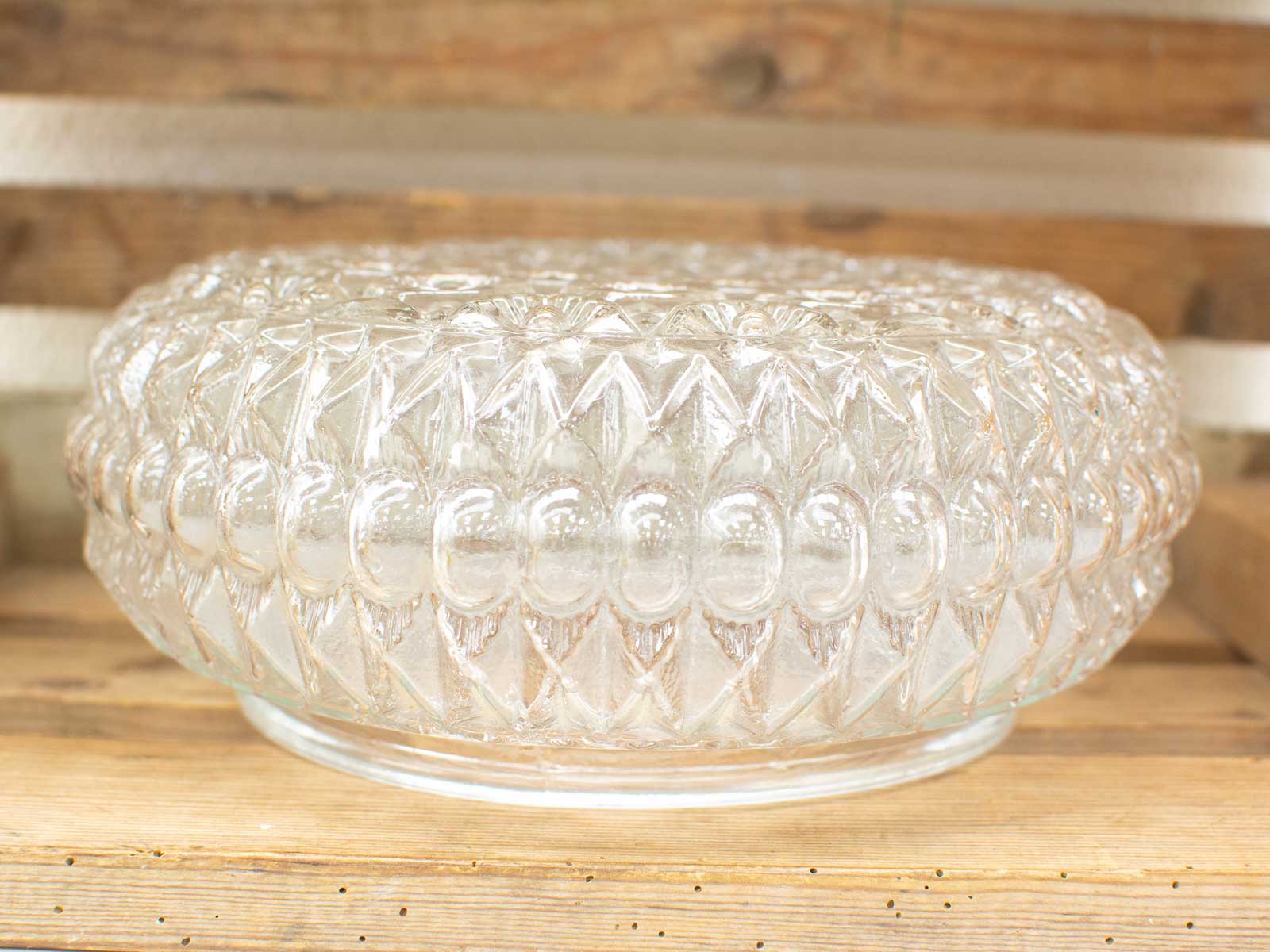 Elegant glass dish with diamond pattern against rustic wooden backdrop, perfect for decor or serving.