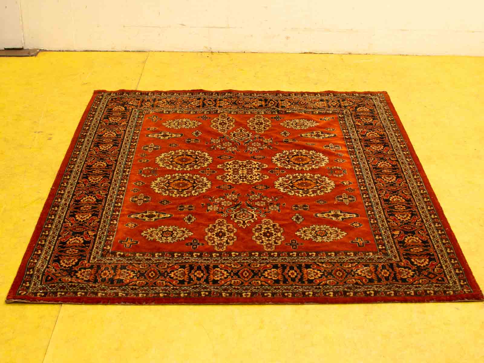 Elegant deep red Persian rug with intricate patterns on a light yellow floor.