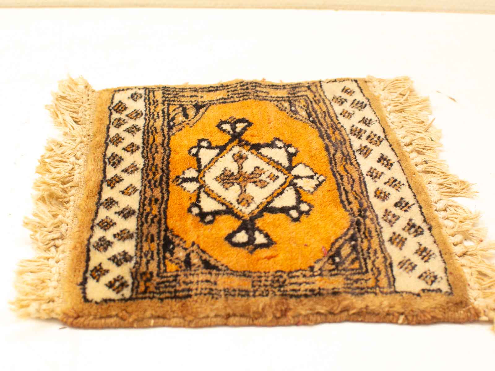 Handwoven orange rug with intricate geometric patterns, traditional motifs, and fringed edges.