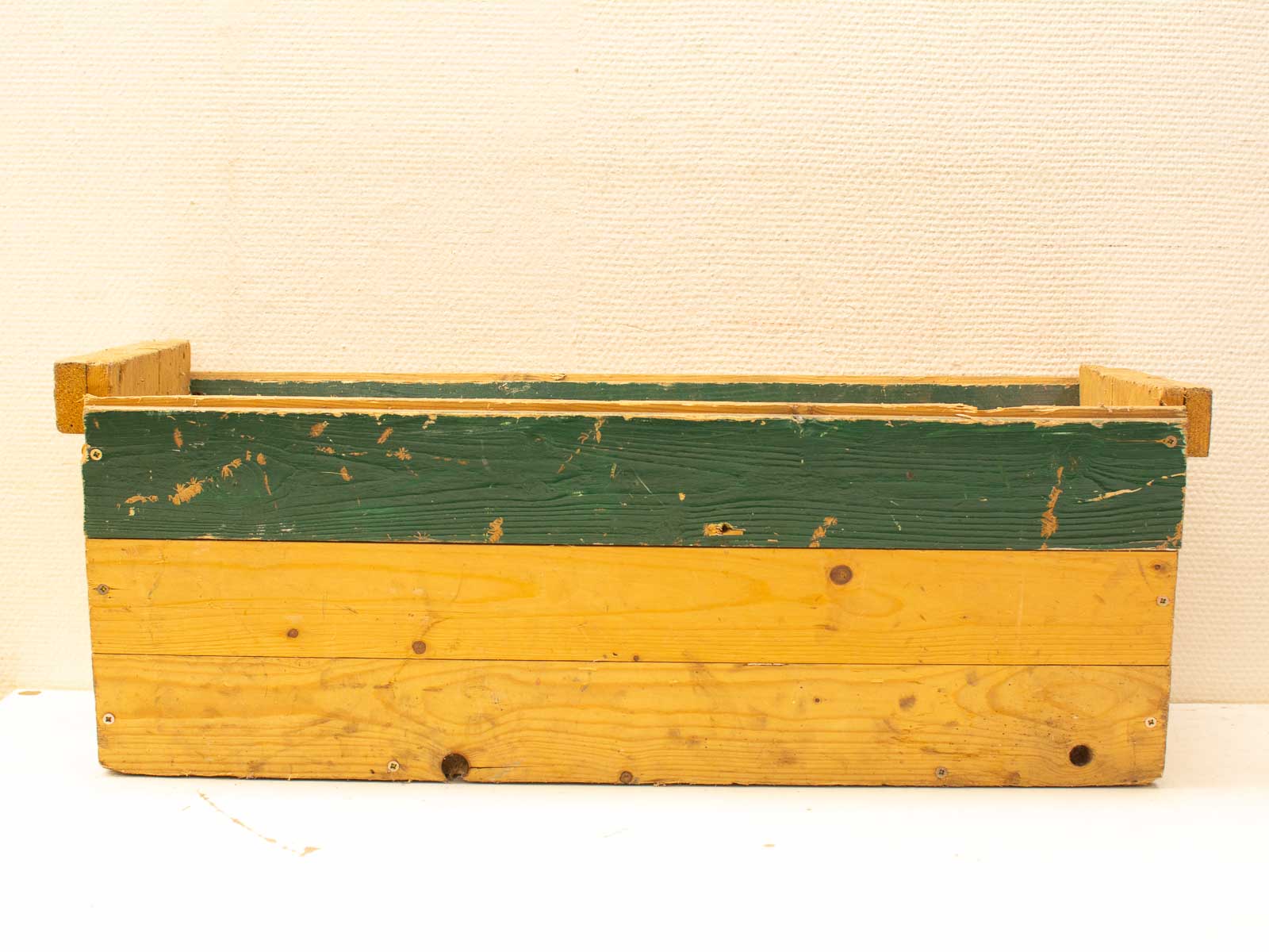 Rustic wooden storage box with worn yellow and green paint, ideal for vintage home decor.