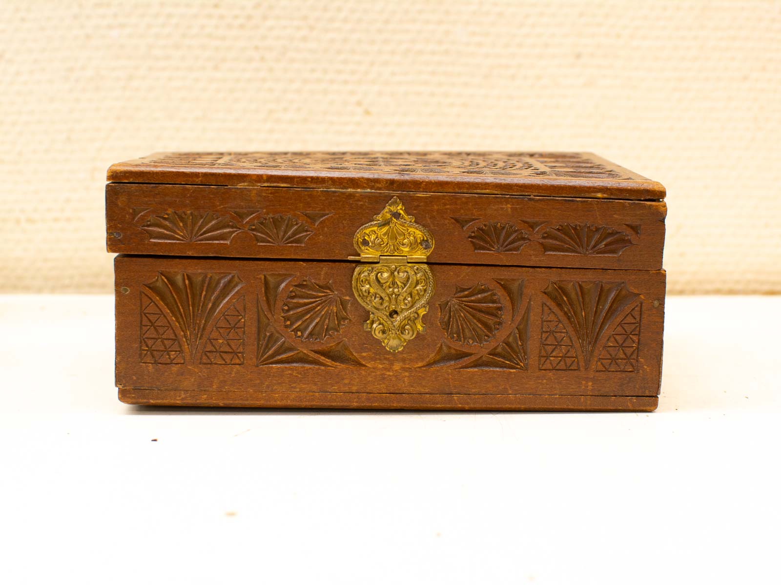 Elegant wooden box with intricate carvings and ornate brass clasp, showcasing exceptional craftsmanship.