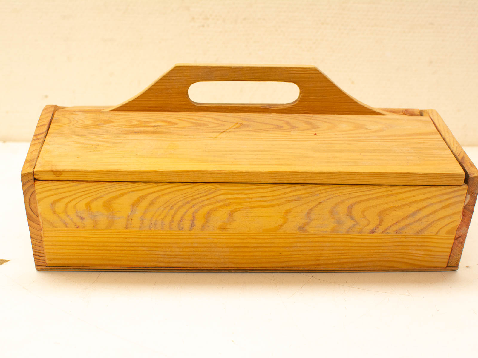 Handcrafted traditional wooden toolbox with integrated handle, showcasing rustic design and charming wear marks.