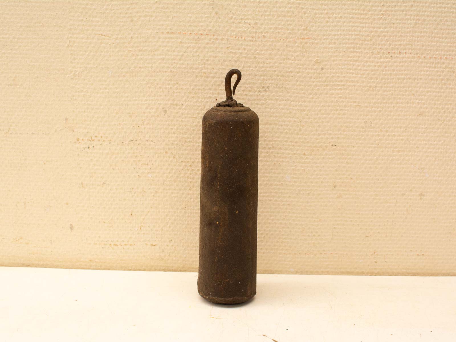 Vintage cylindrical weight with hook, showcasing character and charm for functional or decorative use.