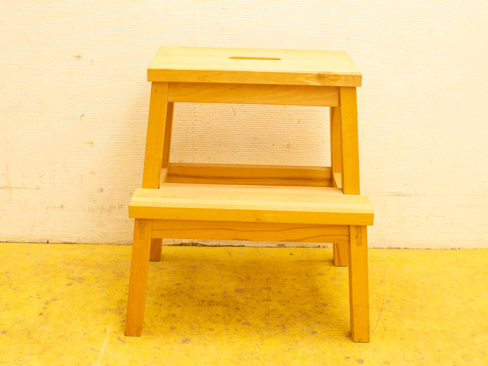 Light wooden step stool with circular handle, ideal for reaching high places and extra seating.