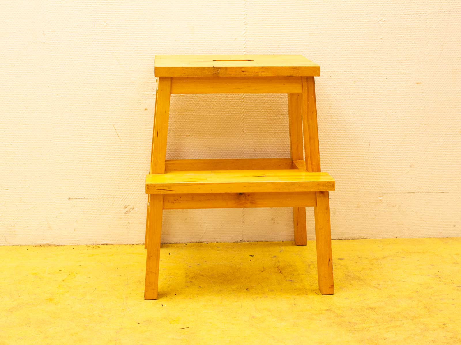 Versatile two-tier wooden stool with yellow accents, featuring a carrying cutout for easy mobility.