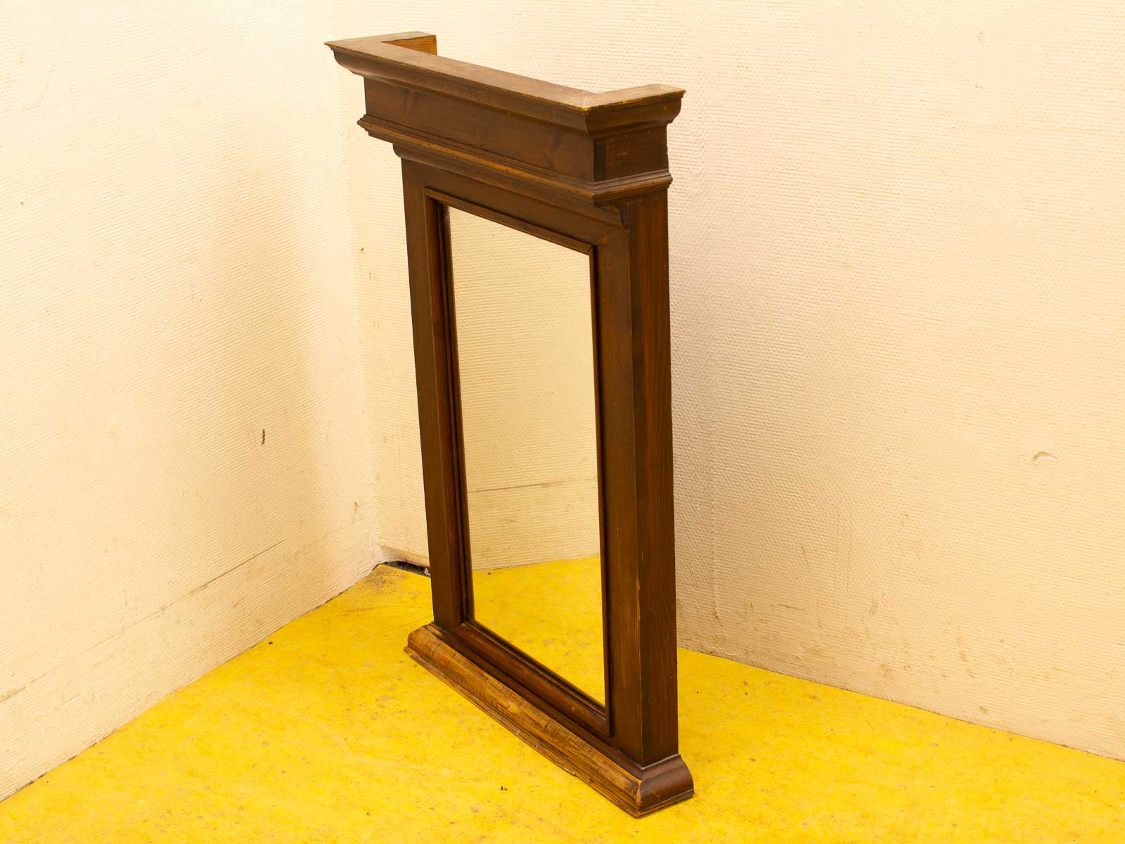 Elegant vintage wooden mirror in a minimalist room with vibrant yellow flooring.