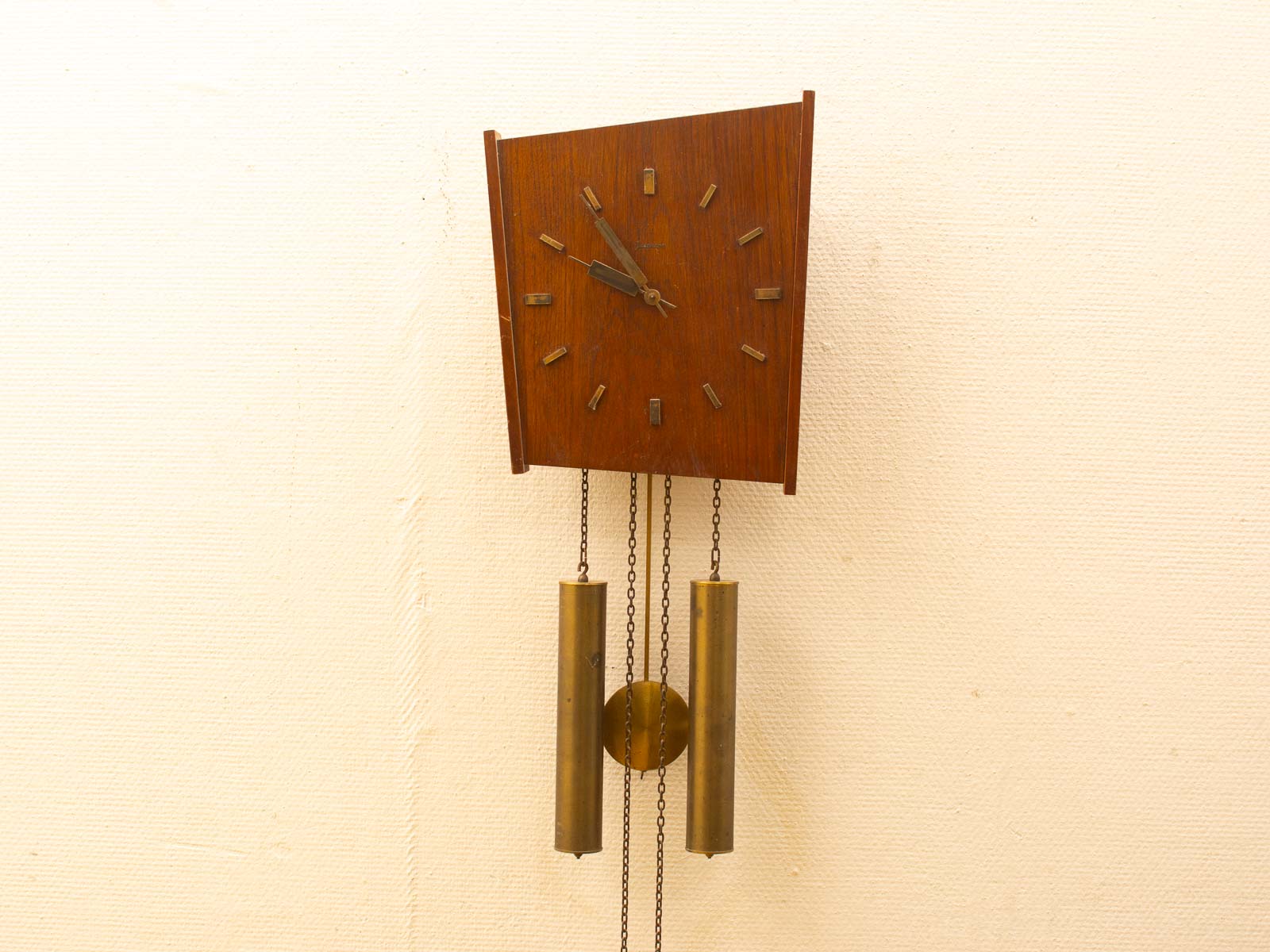 Stylish mid-century modern wall clock with brass pendulums and warm wood finish. Timeless design.