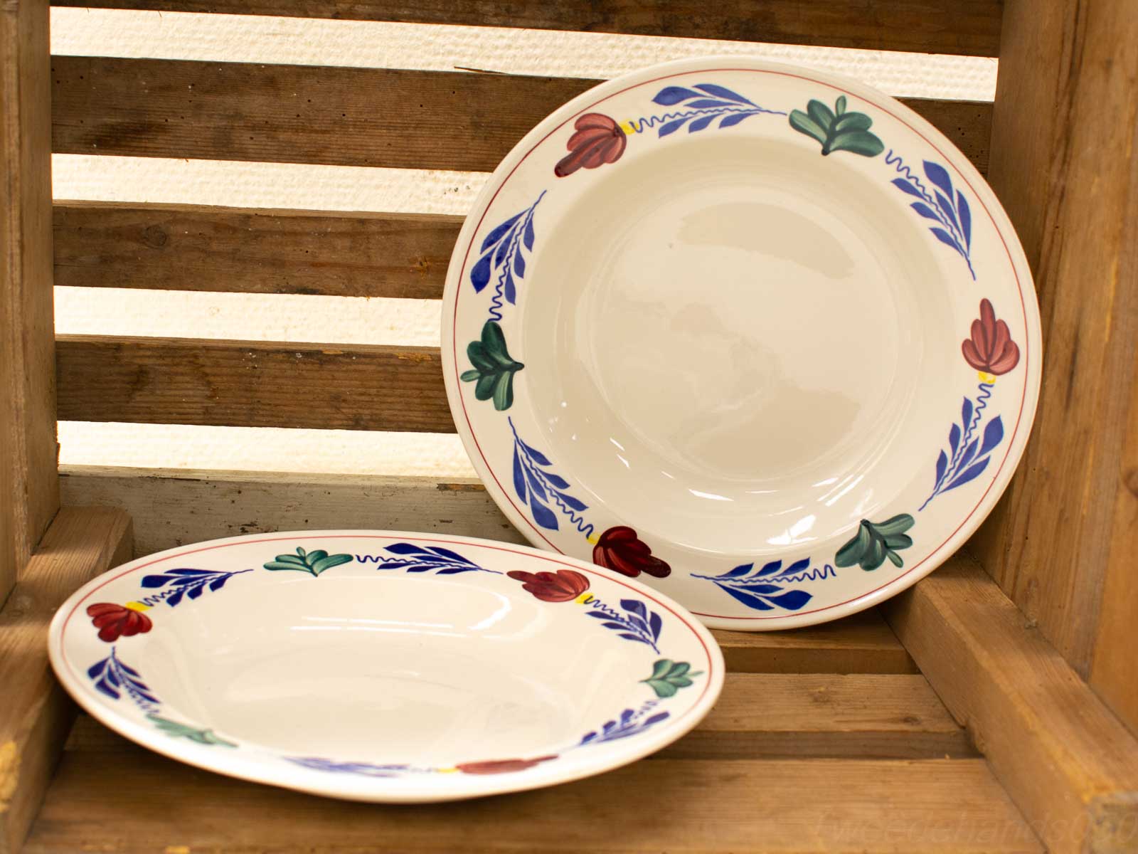 Elegant vintage ceramic plates with floral designs in a rustic wooden crate. Perfect home decor.