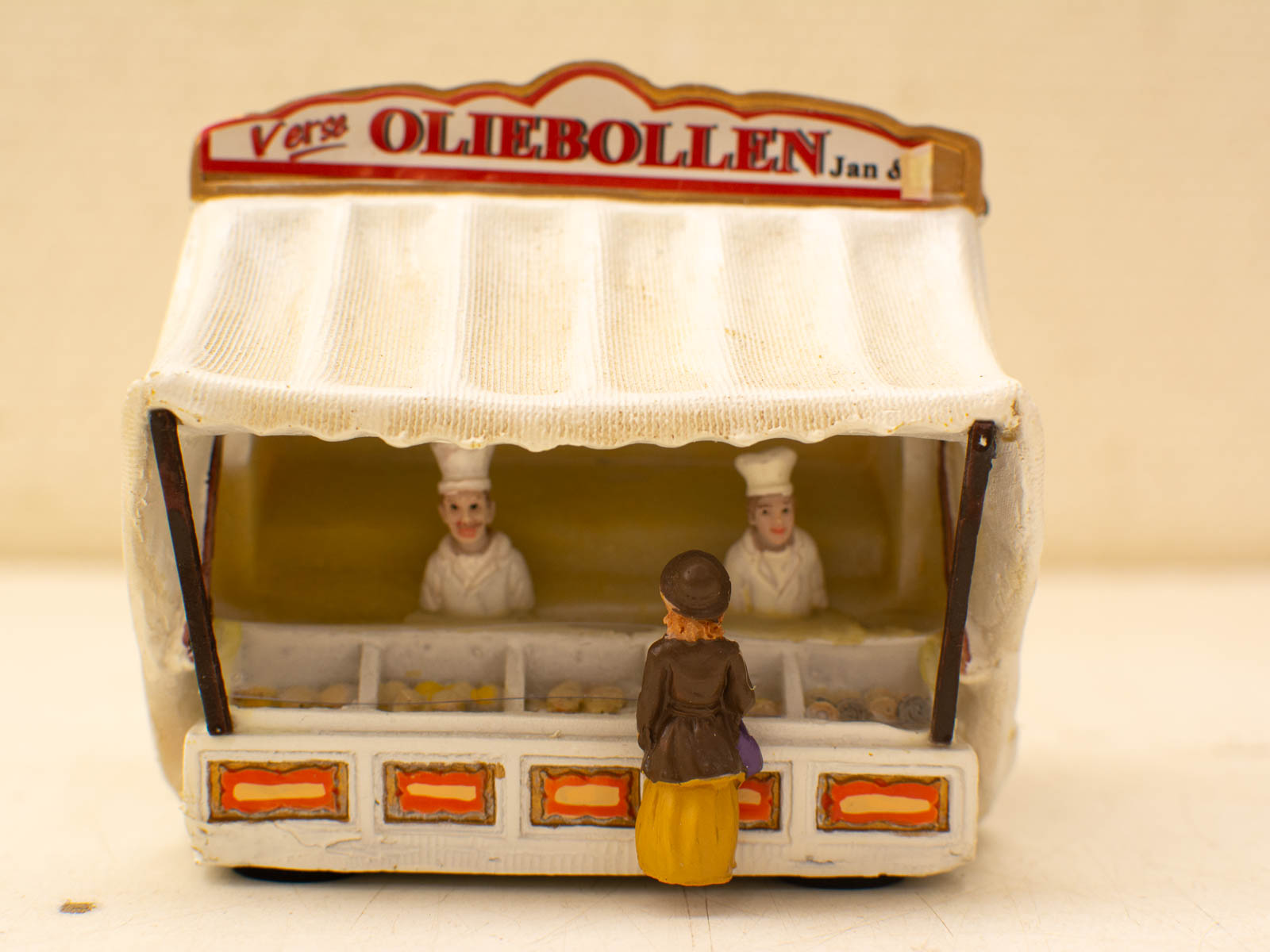 Charming miniature Dutch oliebollen stall with inviting bakers at a festive market scene.