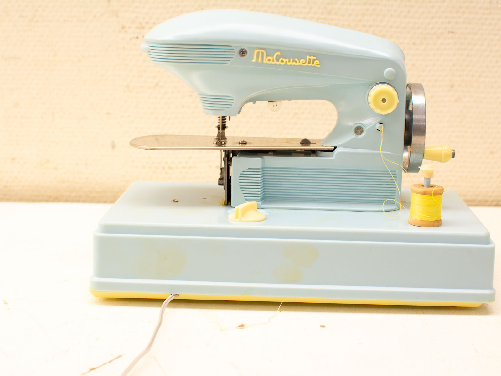 Vintage Malourette sewing machine in light blue with yellow thread, perfect for creative projects.