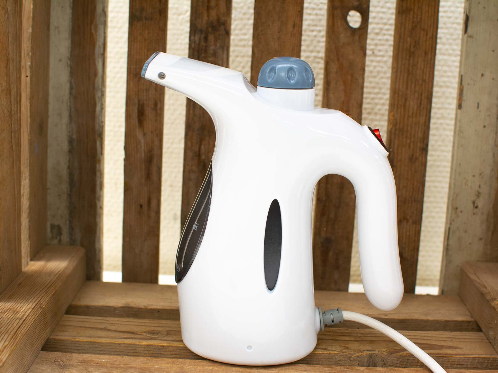 Sleek handheld garment steamer for effortless wrinkle removal, set on a rustic wooden surface.