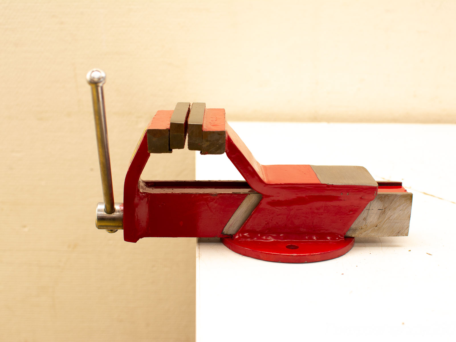 Compact red bench vise for secure gripping in workshops and DIY projects.