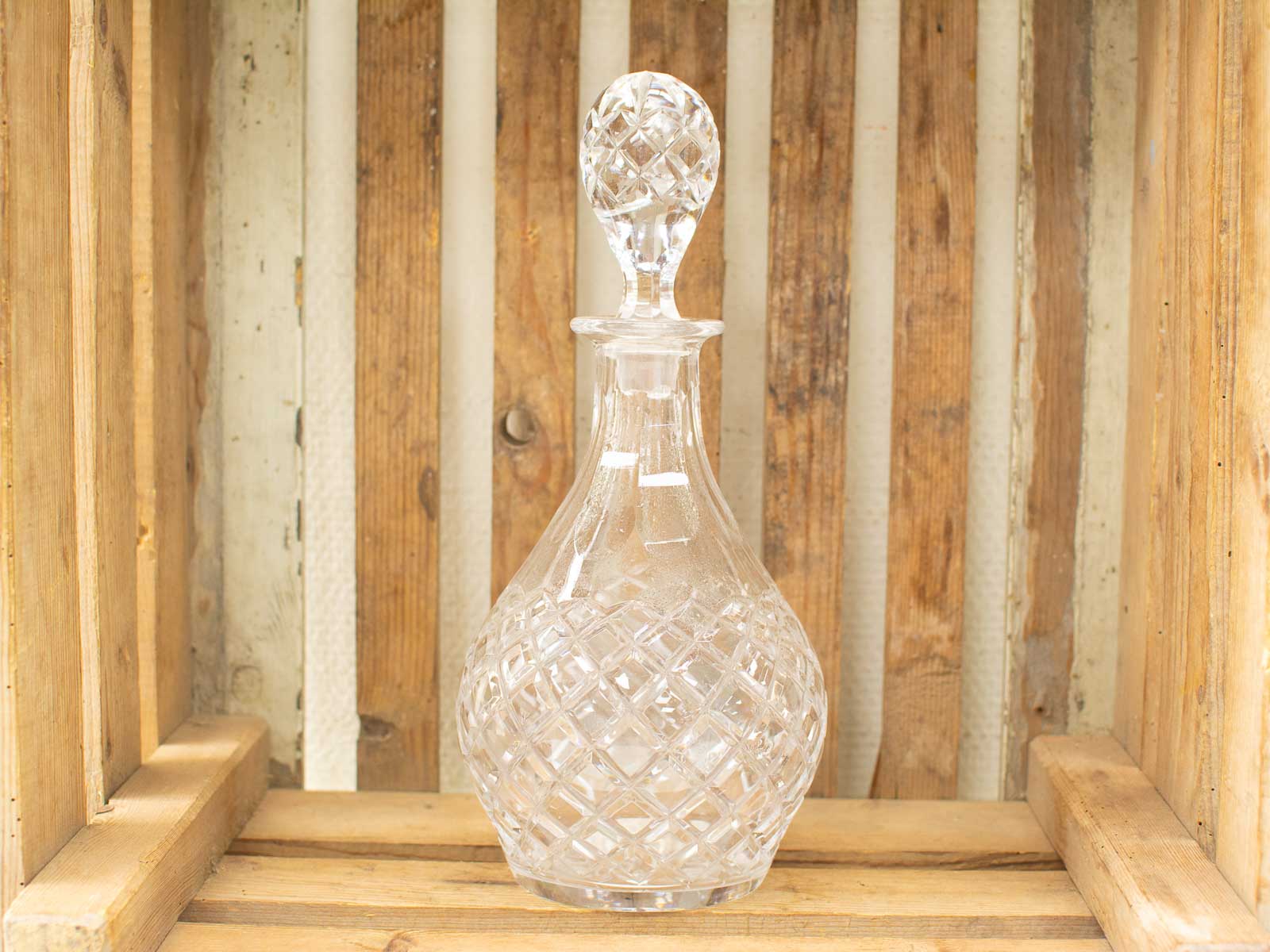 Elegant crystal decanter on a rustic wooden backdrop, showcasing fine craftsmanship and vintage charm.