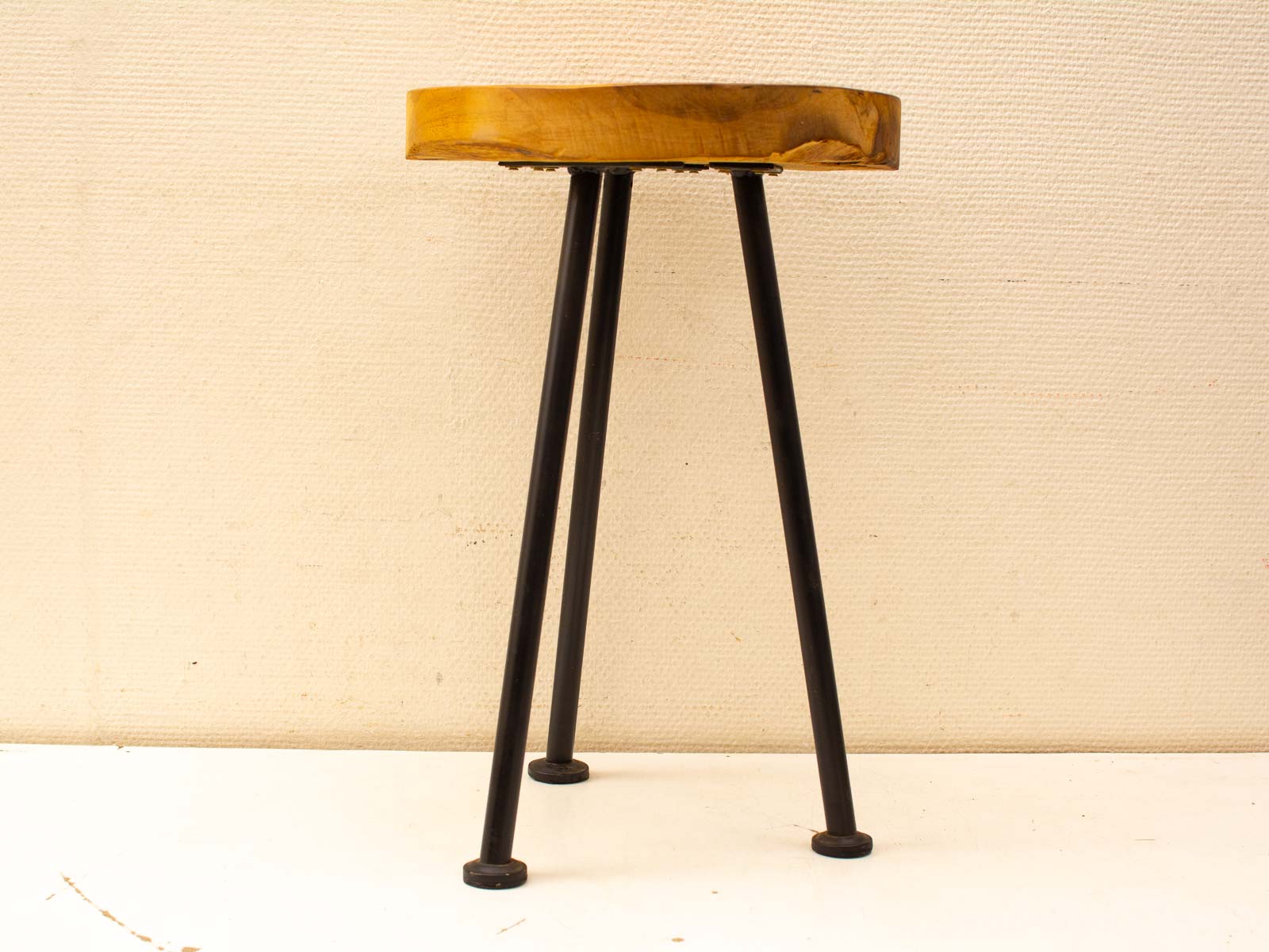 Minimalist wooden stool with sleek black metal legs, perfect for stylish seating and decor.