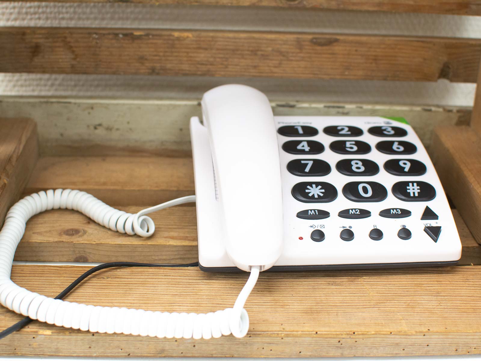 Charming vintage white landline telephone on wood, blending nostalgia and practicality for classic communication.