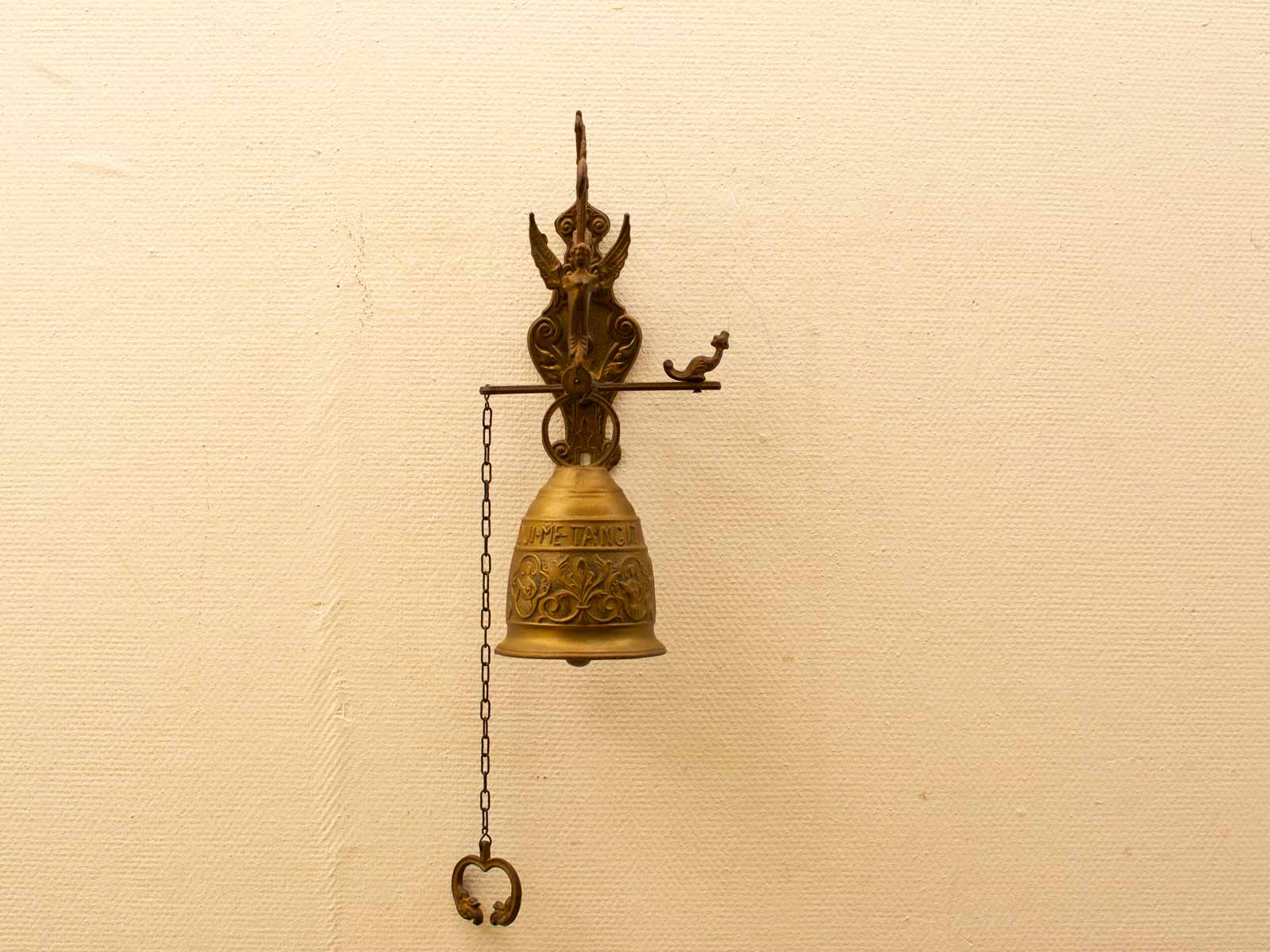 Elegant antique brass bell with intricate engravings and heart-shaped pull for vintage decor.