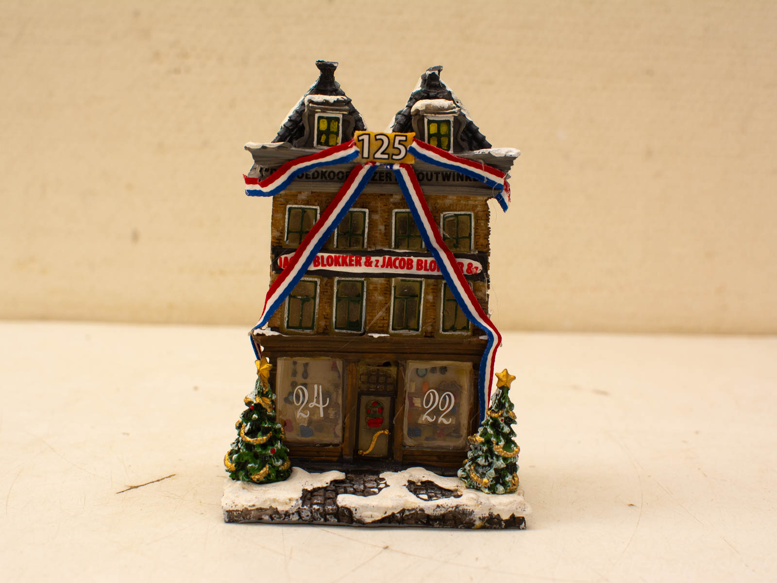 Charming vintage miniature house with winter decorations and anniversary number 125 for festive displays.