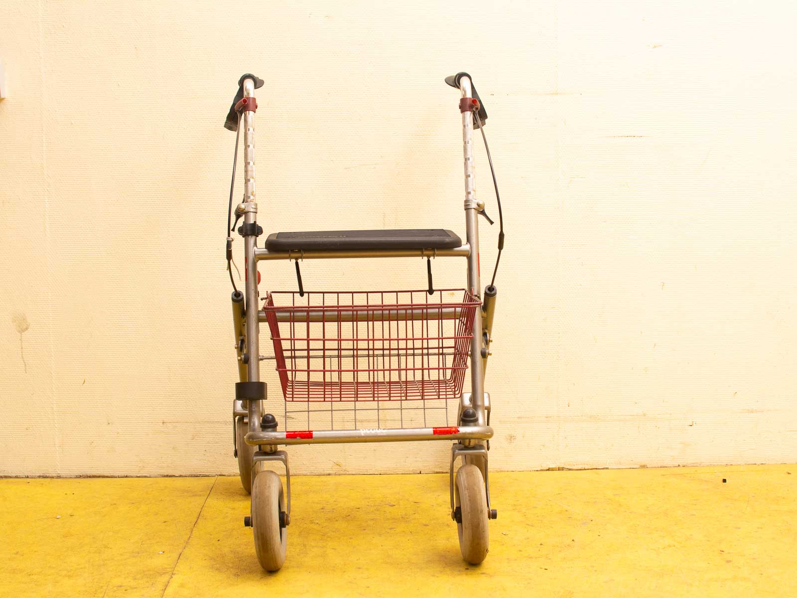 Durable silver walker with wheels, padded seat, and basket for convenient mobility and comfort.