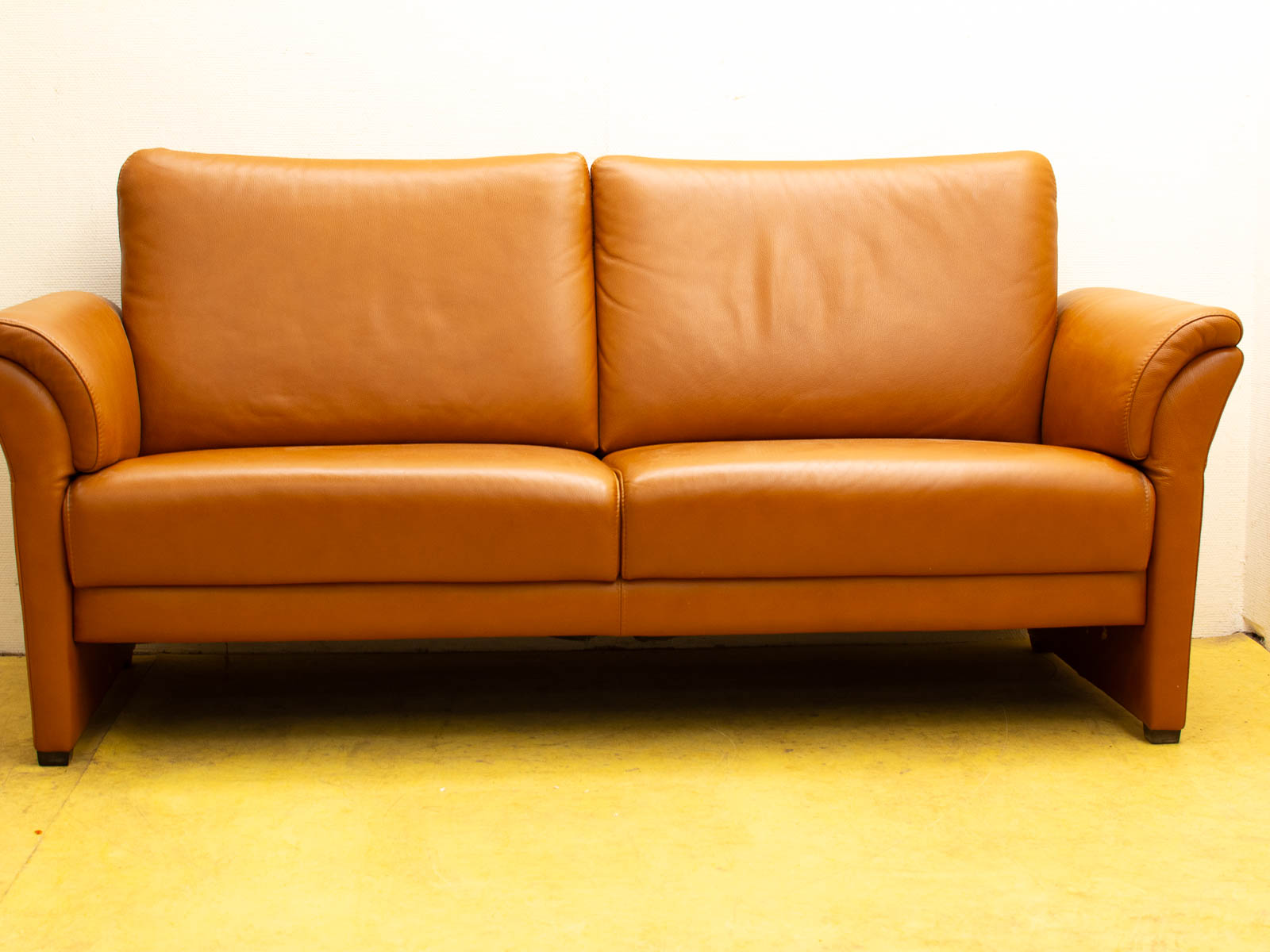 Stylish brown leather two-seater sofa, perfect for modern living rooms and office spaces.