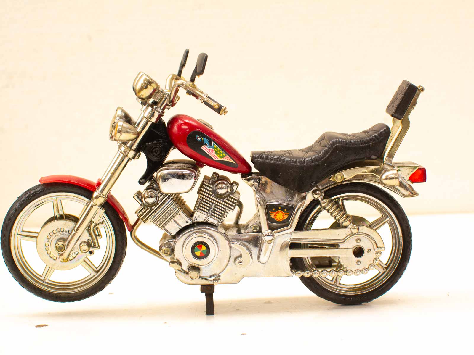 Vintage deep red motorcycle model with bird motif, showcasing intricate details and classic charm.