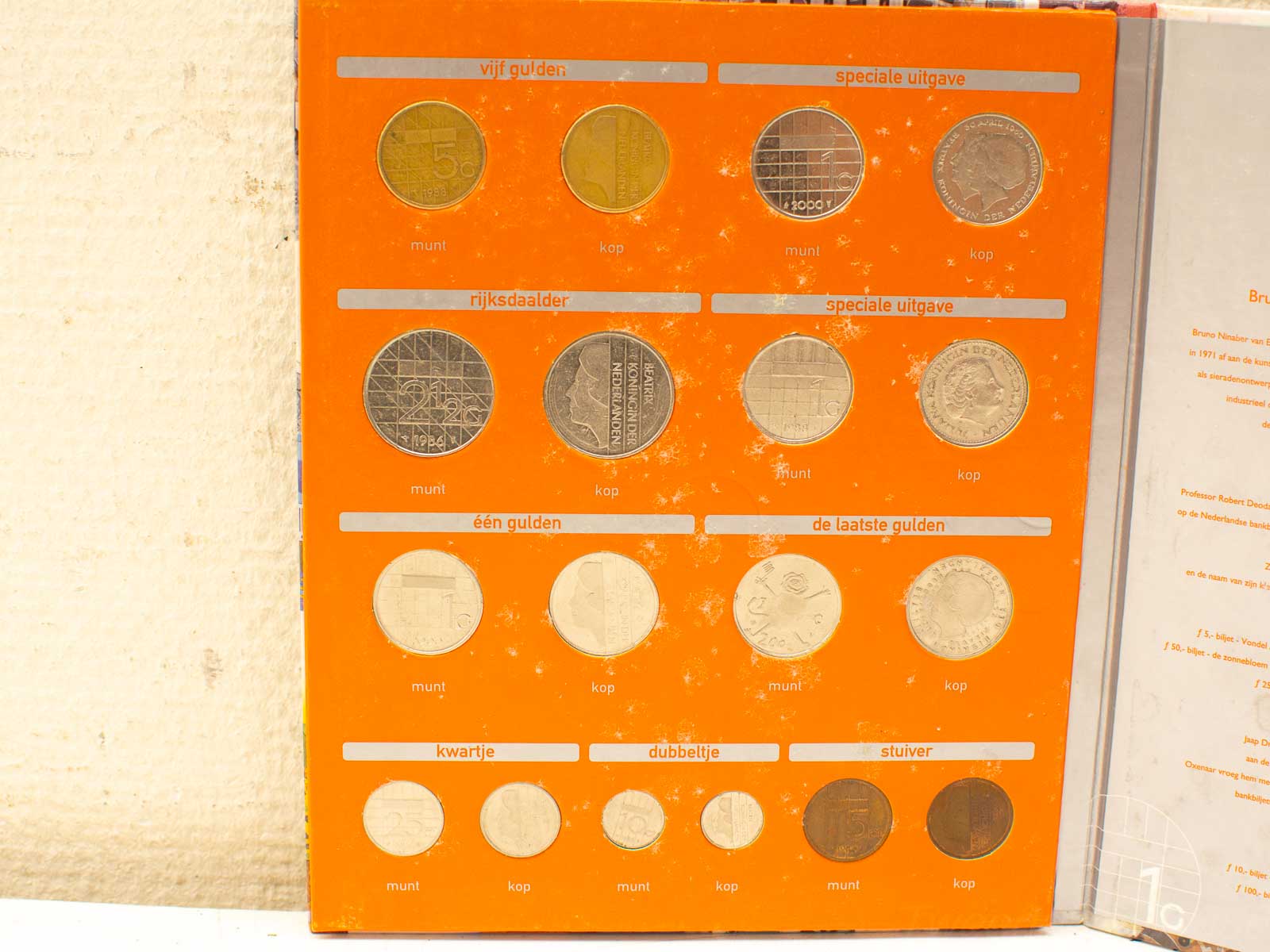 Dutch coin collection in an orange album, featuring historical guilder and kwartje coins.