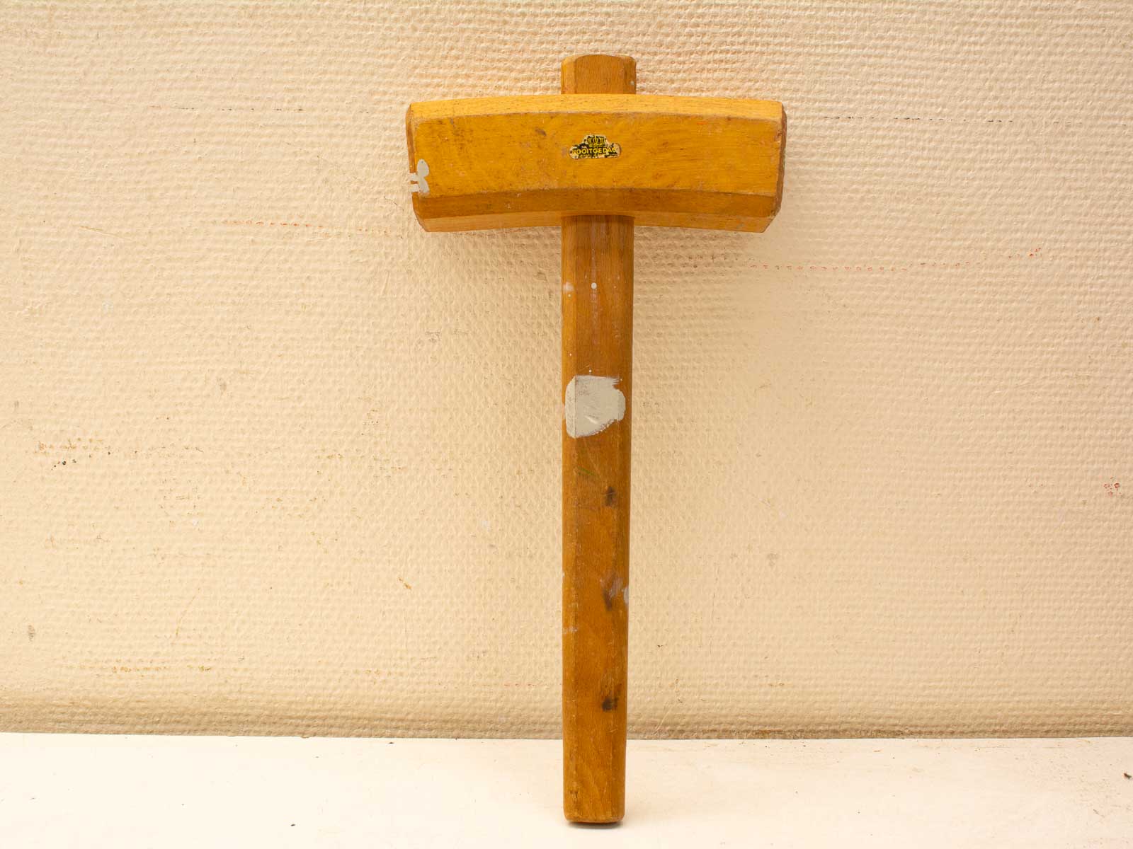 Vintage wooden mallet with yellow head, showcasing wear marks and craftsmanship for woodworking enthusiasts.