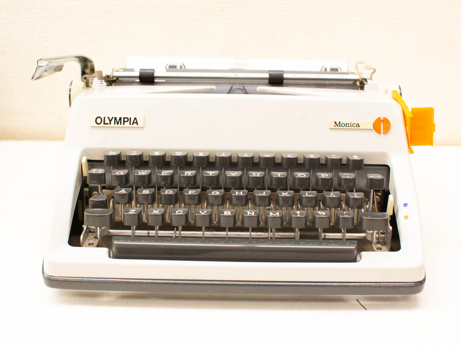 Classic Olympia Monica typewriter, vintage charm with black keys and playful orange button.