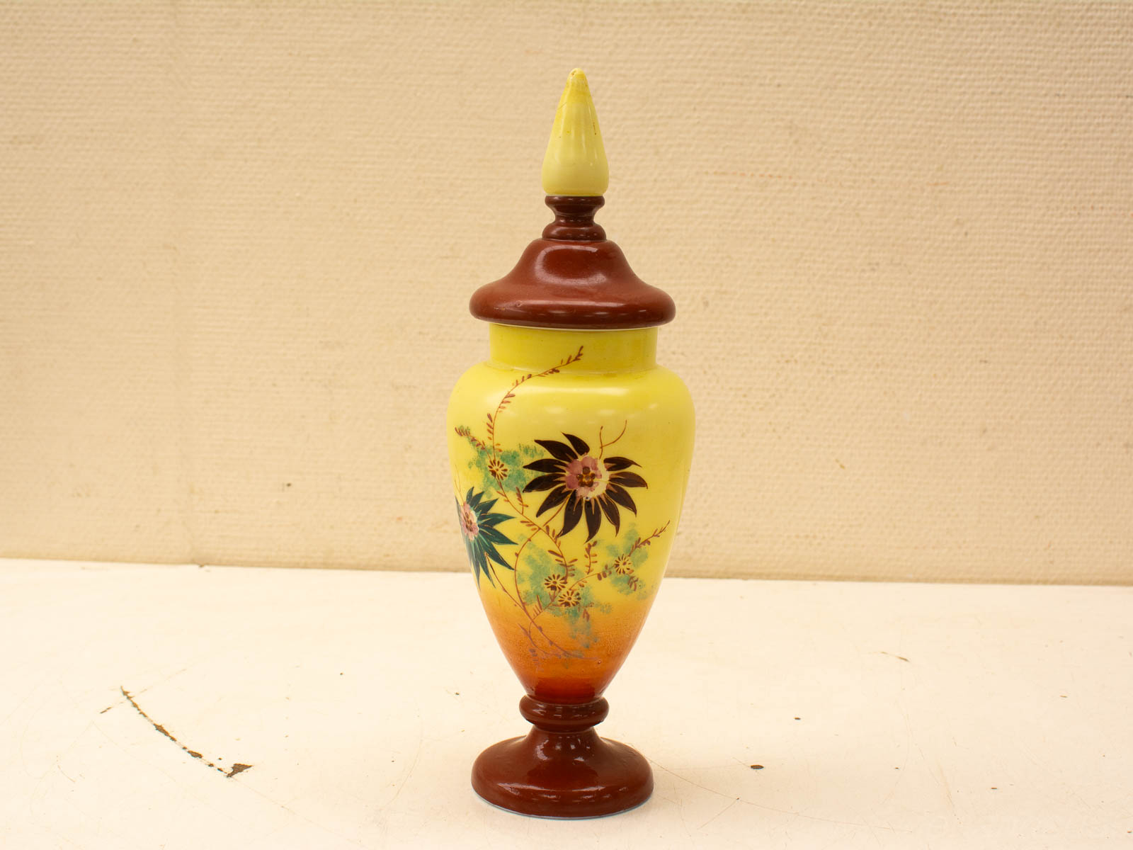 Elegant Yellow Vase with Floral Design and Brown Lid, Showcasing Artistry and Aesthetic Appeal.