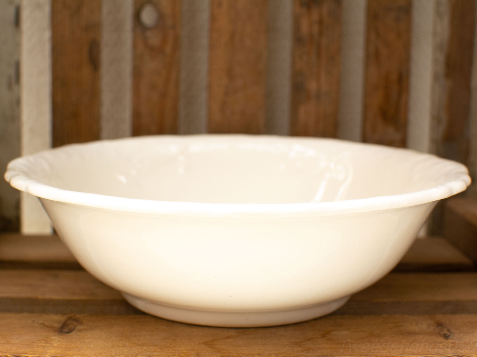 Classic white ceramic bowl on rustic wooden backdrop, perfect for serving various dishes.