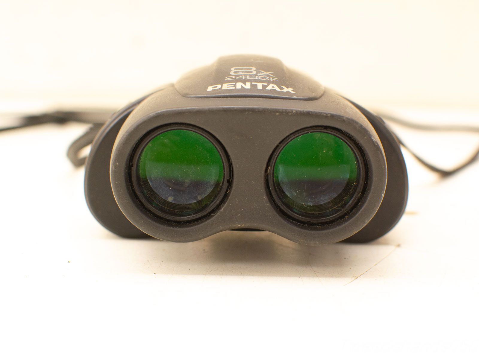 Sleek PENTAX 8x binoculars with green-tinted lenses for enhanced clarity and outdoor adventures.