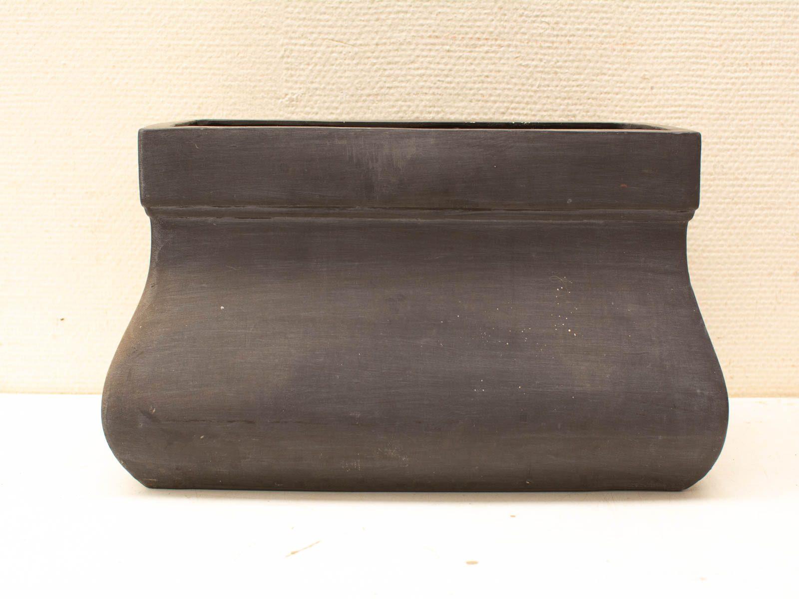 Handmade, dark matte ceramic pot with rustic modern aesthetics, suitable as a planter or decor piece.