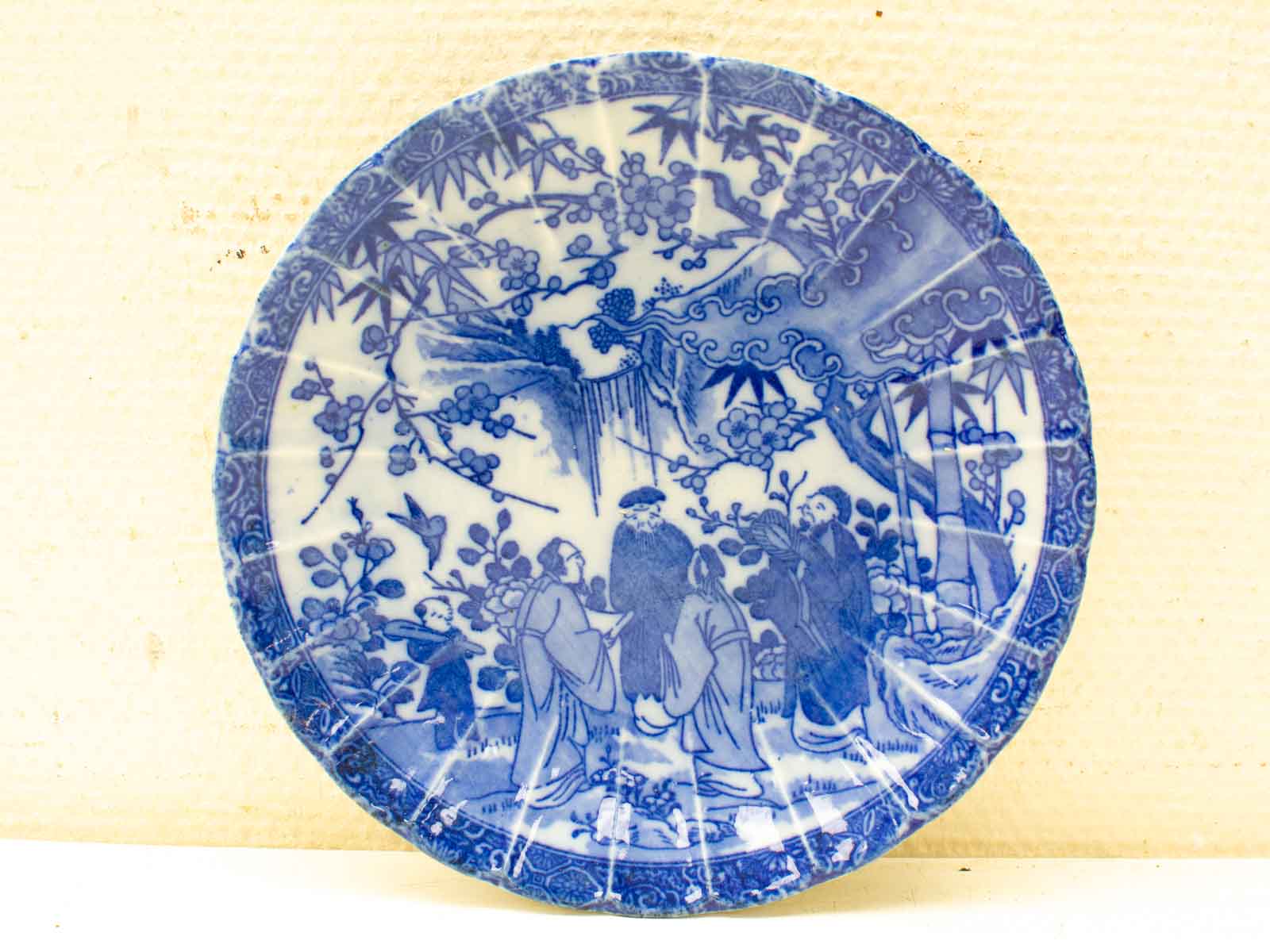 Elegant blue and white porcelain plate featuring Chinese scholars in a serene natural setting.