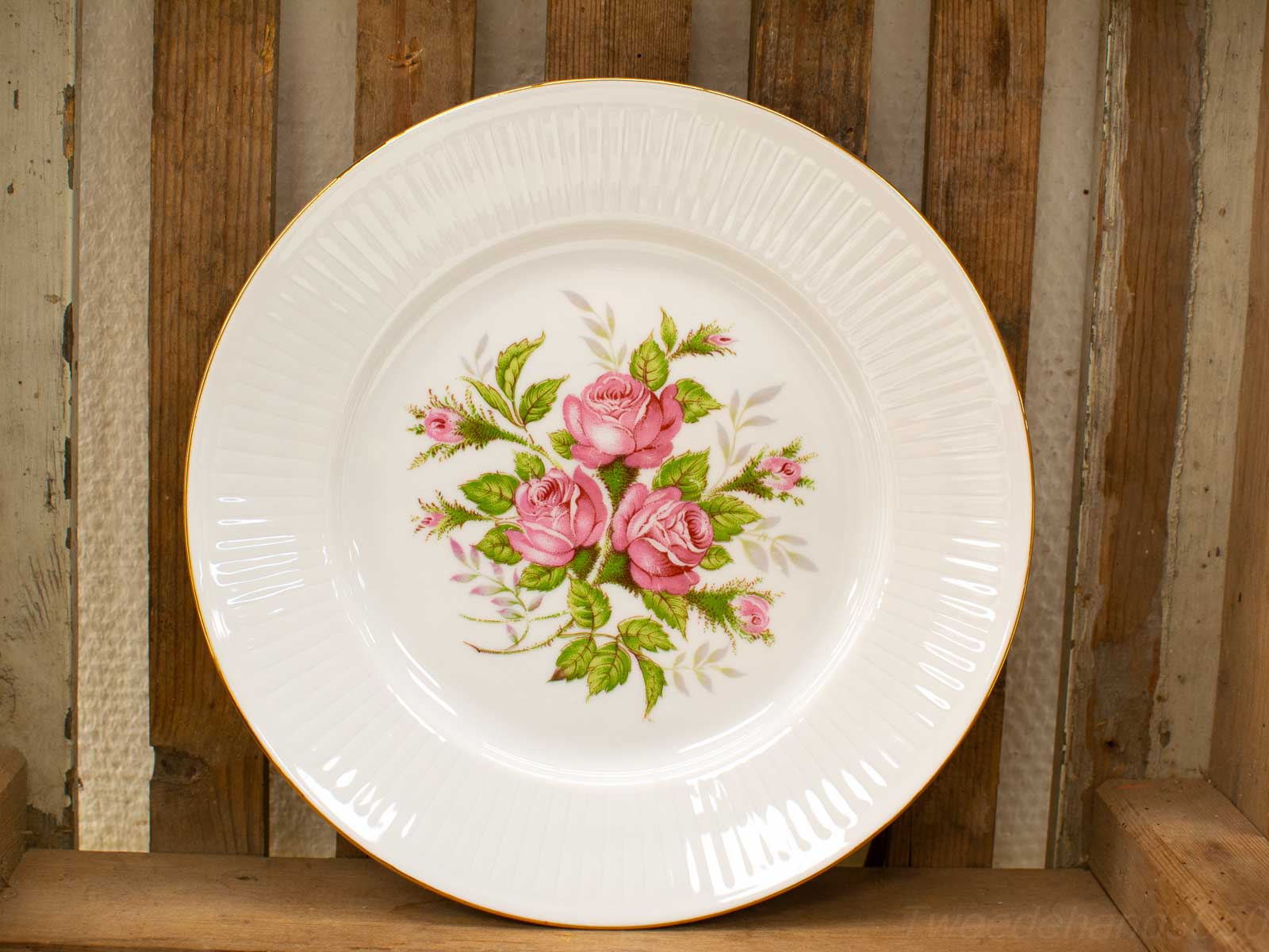 Elegant porcelain plate with pink rose motif and gold rim, perfect for display or dining.