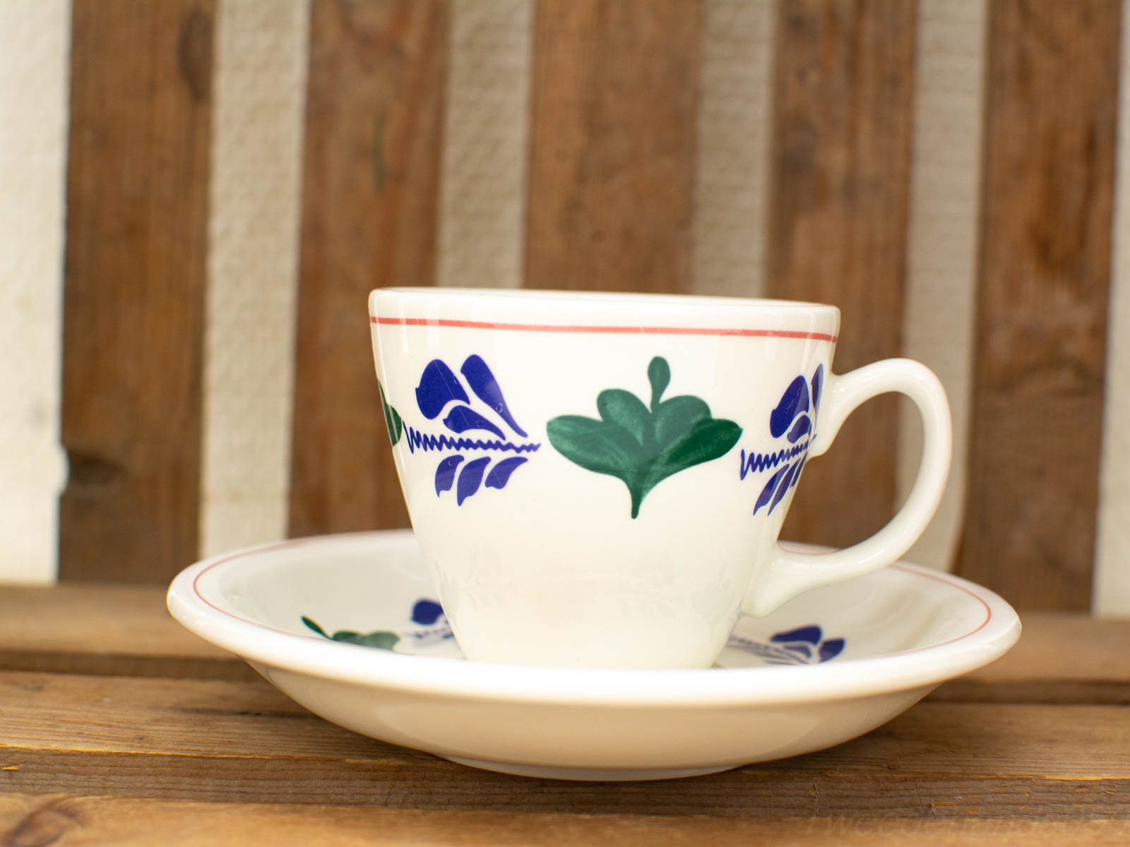 Elegant porcelain cup and saucer set with vibrant blue and green floral designs.