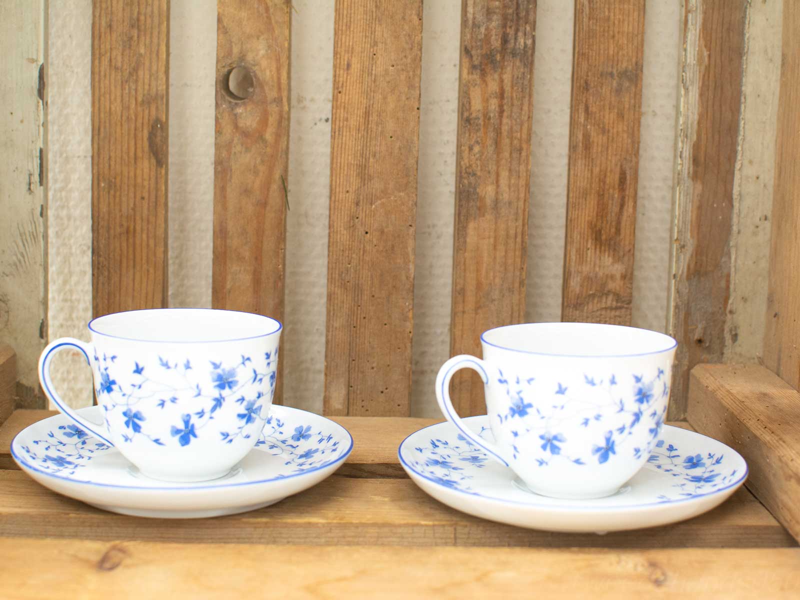 Elegant blue floral porcelain tea cups on rustic wood, perfect for a charming tea experience.