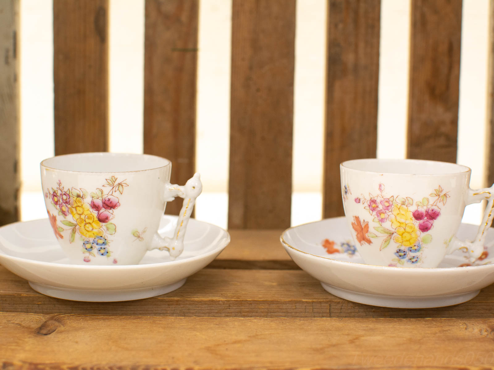 Elegant porcelain tea cups with floral designs on rustic wood, ideal for a cozy tea time.