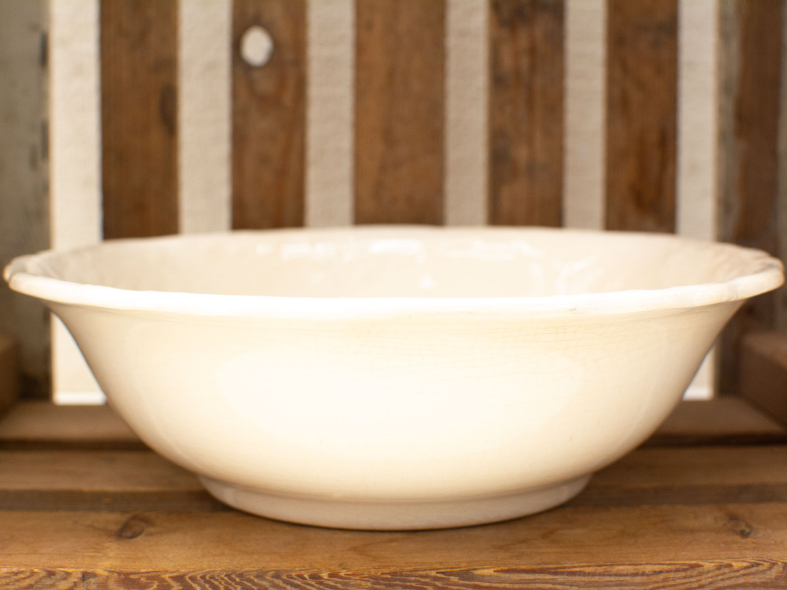 Antique white glossy bowl on rustic wooden background, ideal for serving salads or displaying fruits.