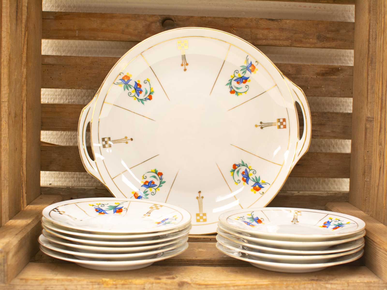 Vintage floral porcelain dishware in rustic wooden crate, perfect for colorful gatherings and cozy dinners.