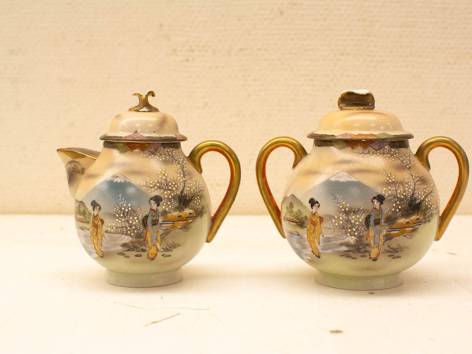 Traditional Asian porcelain teapot and sugar bowl set, adorned with hand-painted figures and landscapes.