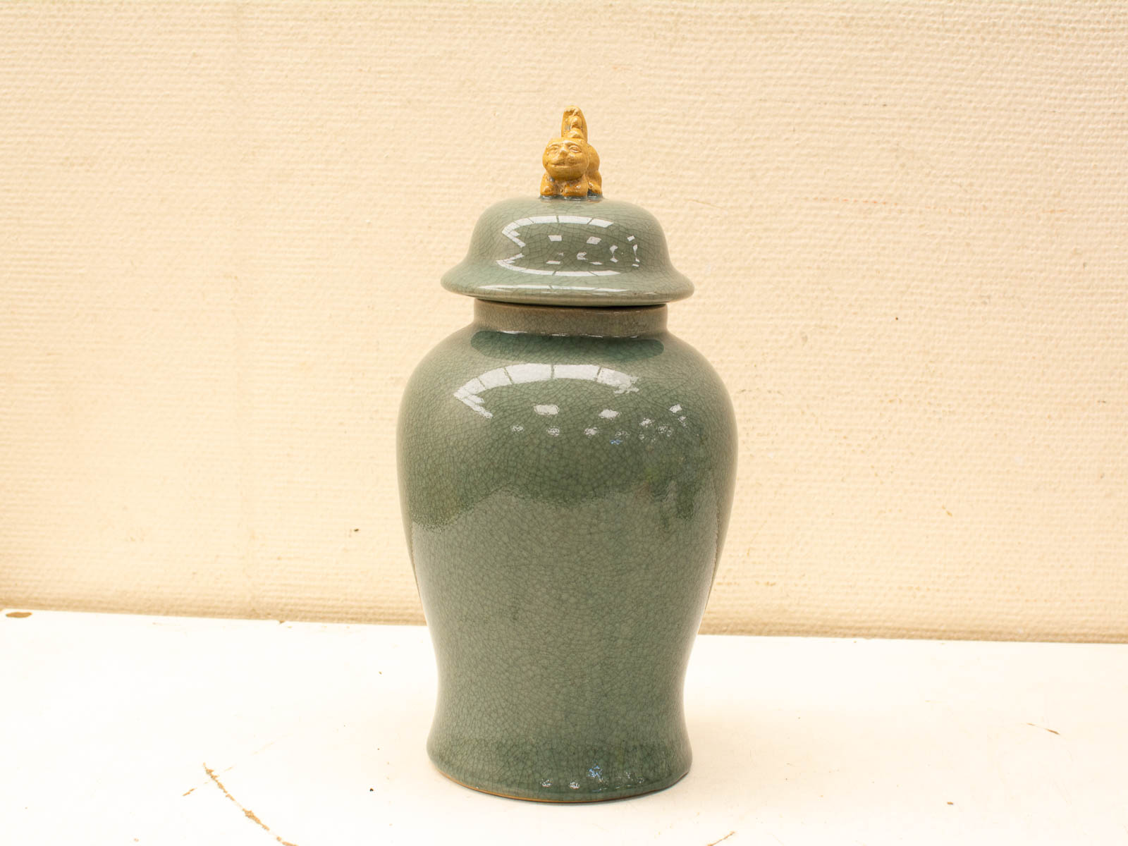 Elegant green vase with lid and decorative finial, featuring a unique crackle glaze.