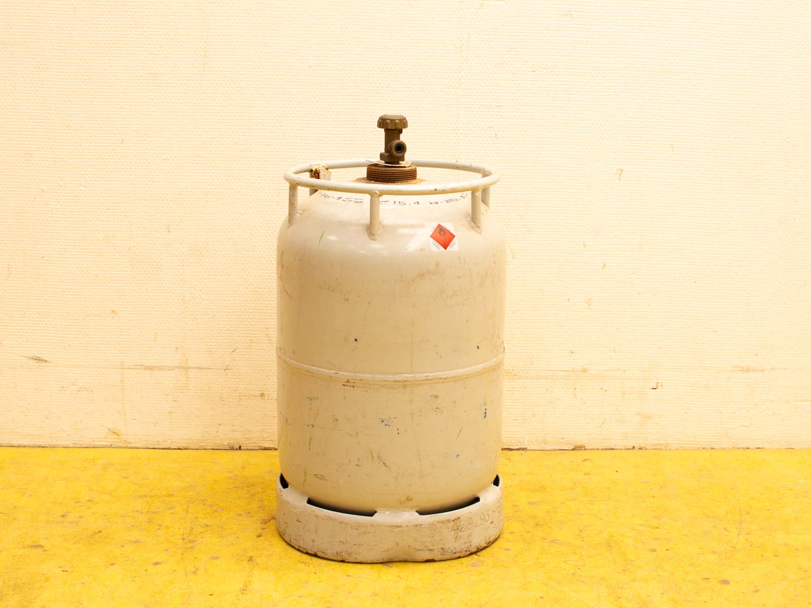 Vintage LPG gas cylinder with brass valve in a practical garage setting.