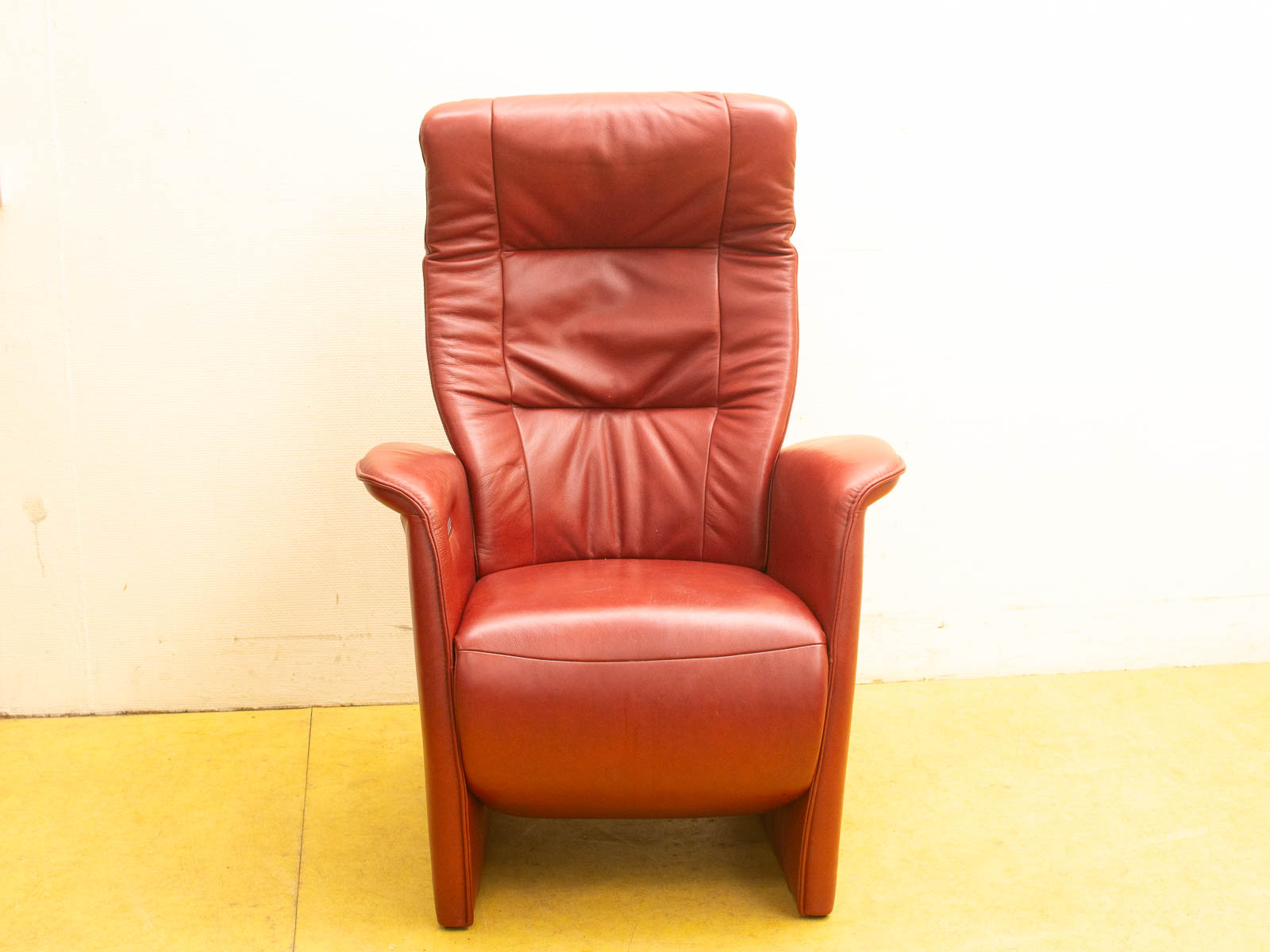 Stylish red leather armchair featuring high backrest and wide arms for ultimate comfort and relaxation.