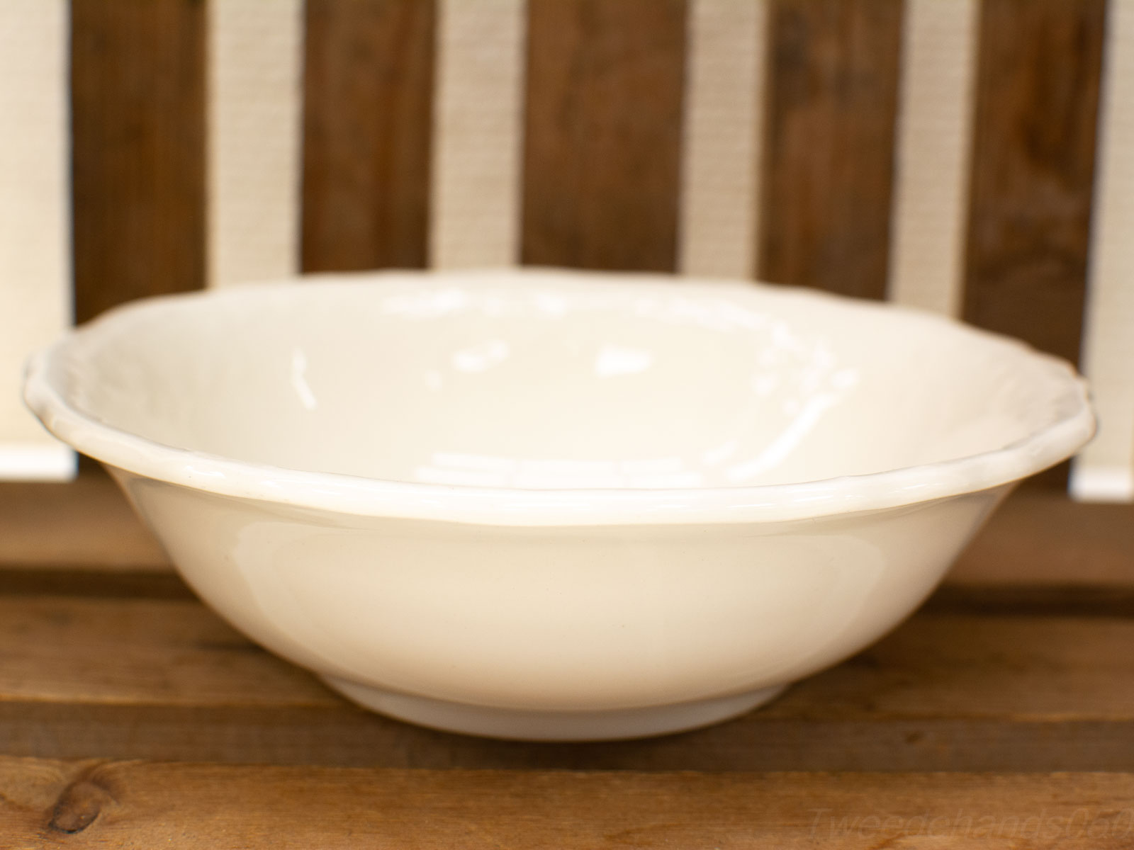 Classic white porcelain bowl with scalloped edge on rustic wooden background.