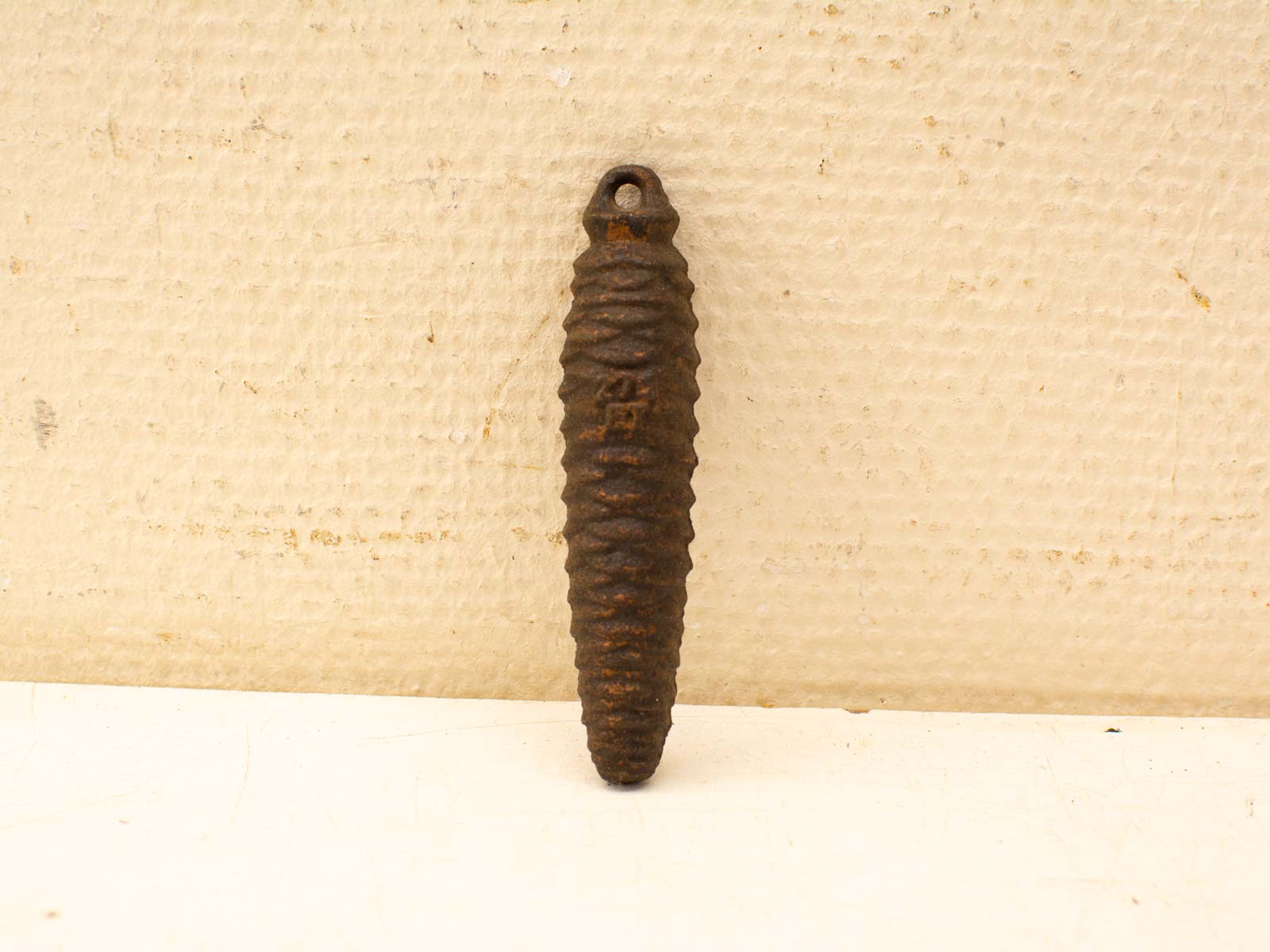 Decorative vintage rusted metal piece with spiral ridges and loop for hanging.