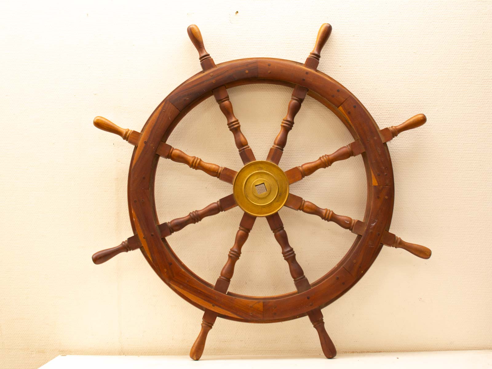 Vintage wooden ships wheel with brass hub, perfect for nautical decor and maritime enthusiasts.