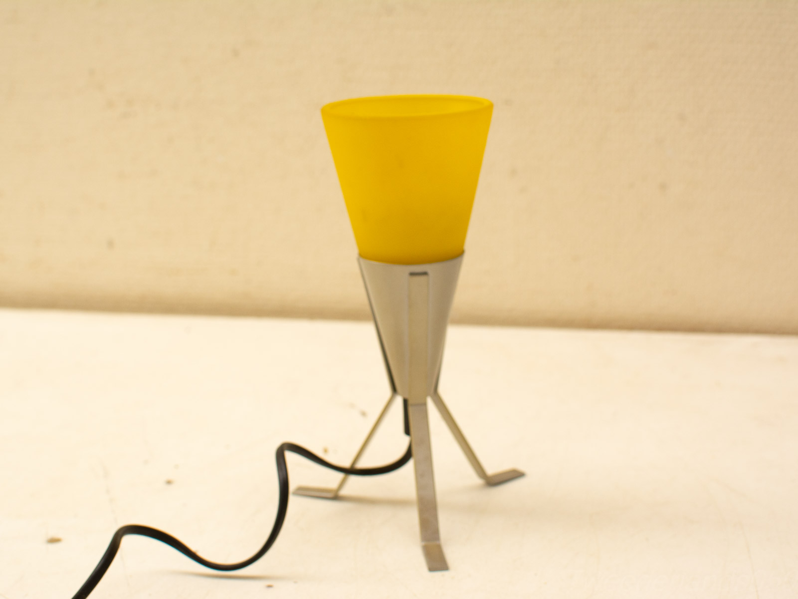 Stylish yellow table lamp with metallic tripod base, ideal for modern and vibrant decor.