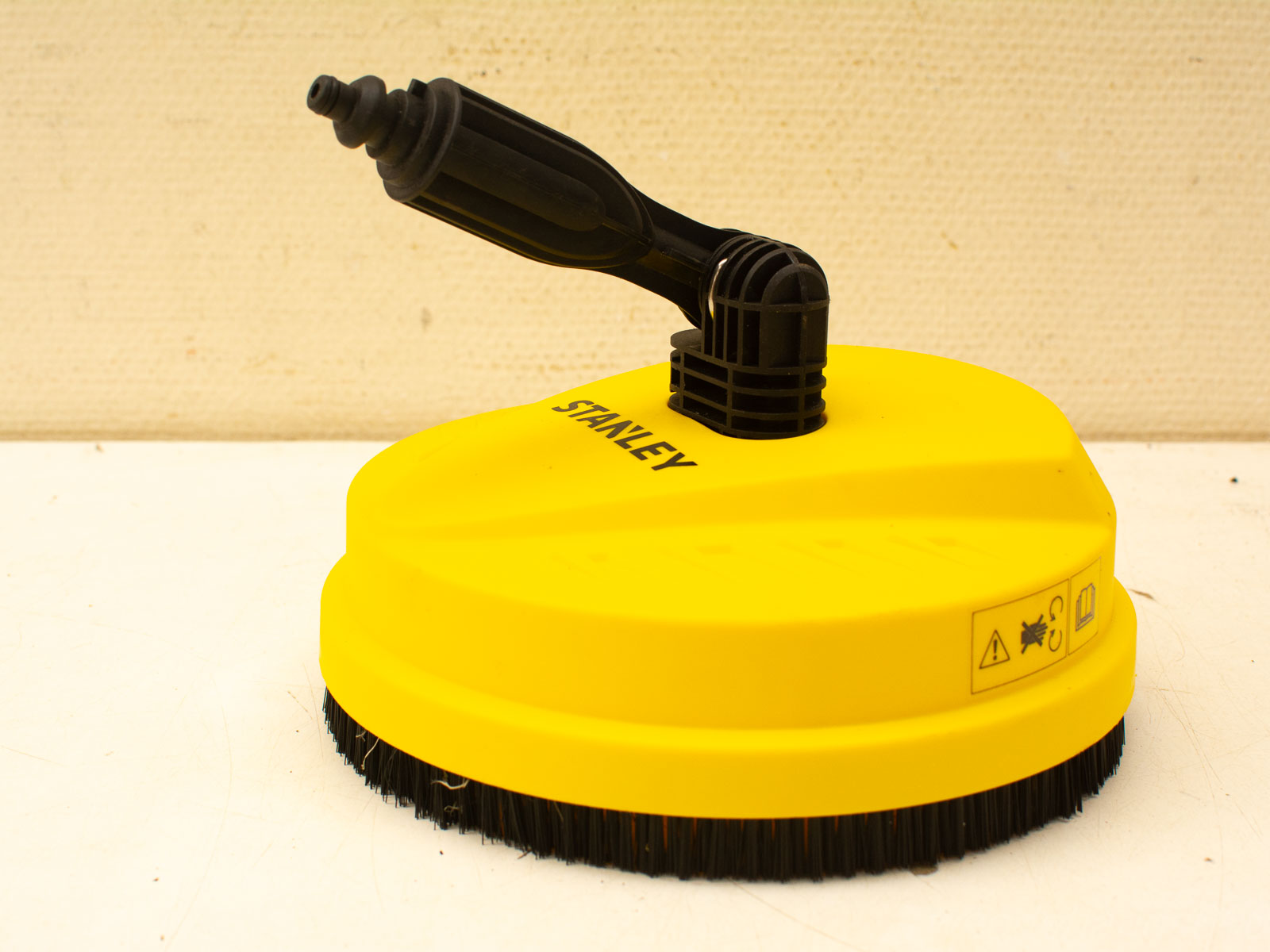 Bright yellow pressure washer brush for effective outdoor cleaning on driveways and patios.