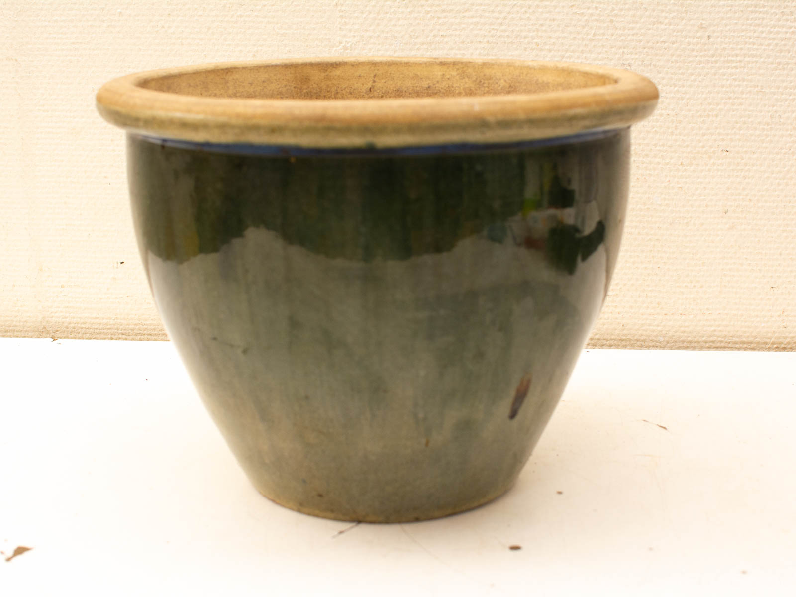 Elegant green ceramic pot with beige rim, perfect for indoor or outdoor plant displays.