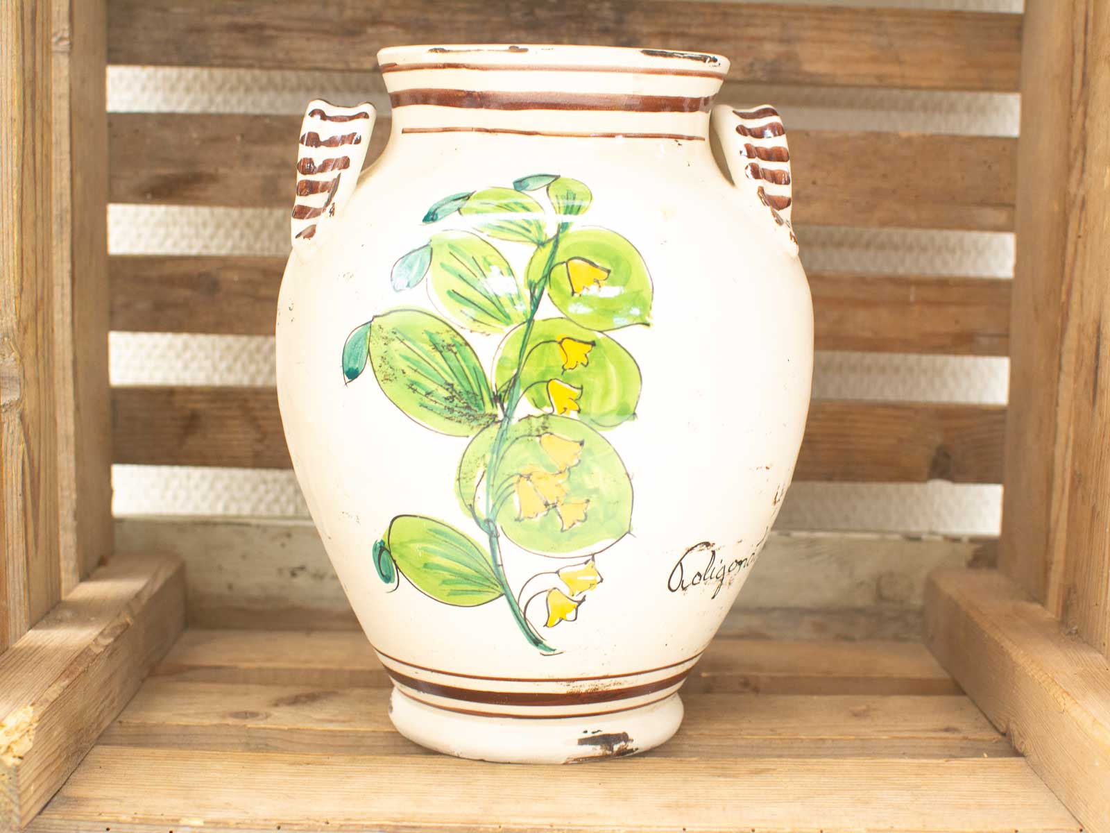 Handcrafted ceramic vase with floral design, rustic charm, and artisan details in wooden crate.